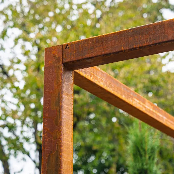 Rust-colored corten steel garden pergola against a blurred green tree background